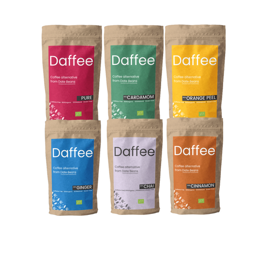 Zes verpakkingen Daffee koffiealternatief met verschillende smaken, kleurrijk geëtiketteerd: Pure, Kardemom, Sinaasappelschil, Gember, Chai, Kaneel.
